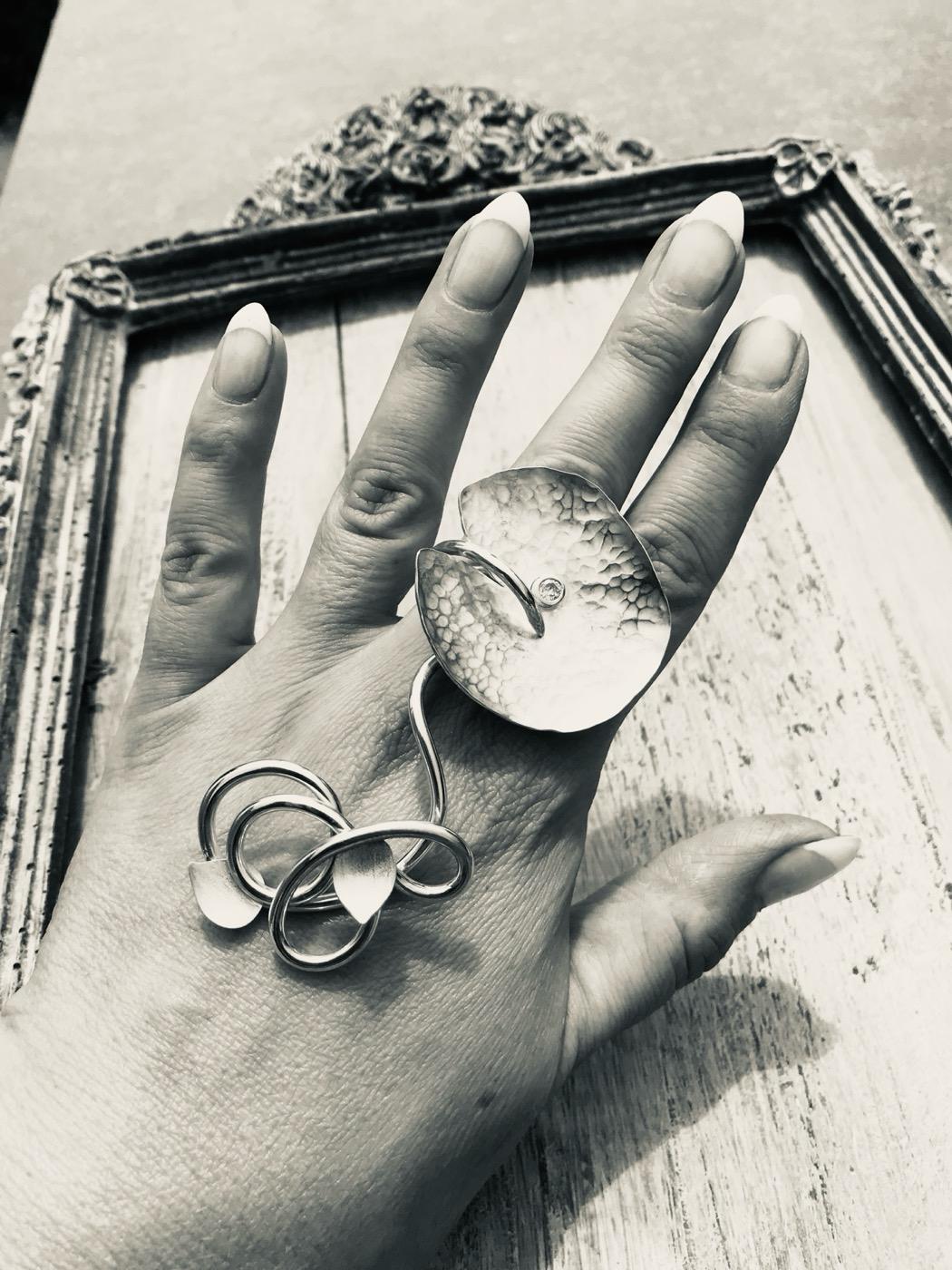 Een gehamerde zilveren ring met een sierlijke krul, aan de hand